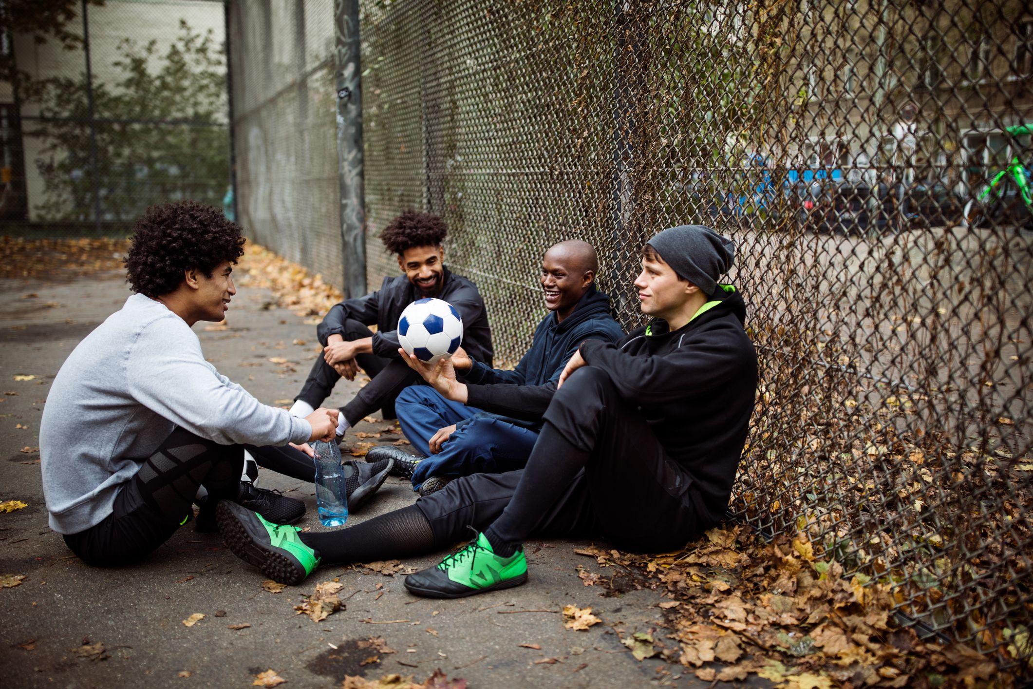 Soccer players talking while sitting against fence Soccer players talking while sitting against fence