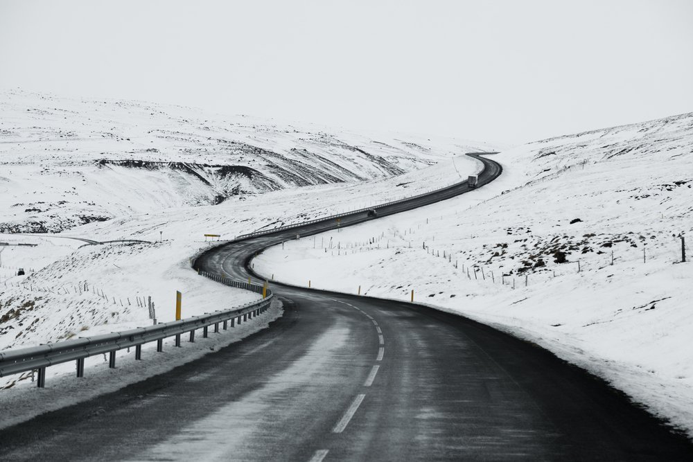 Uphill road landscape in winter at Iceland. Asphalt road with sideways full of snow