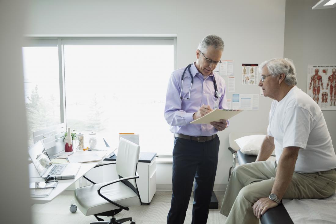 Mature male patient sitting on bed in doctor's office while he looks like clipboard
