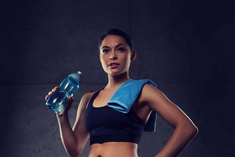 woman-with-towel-drinking-water-from-bottle