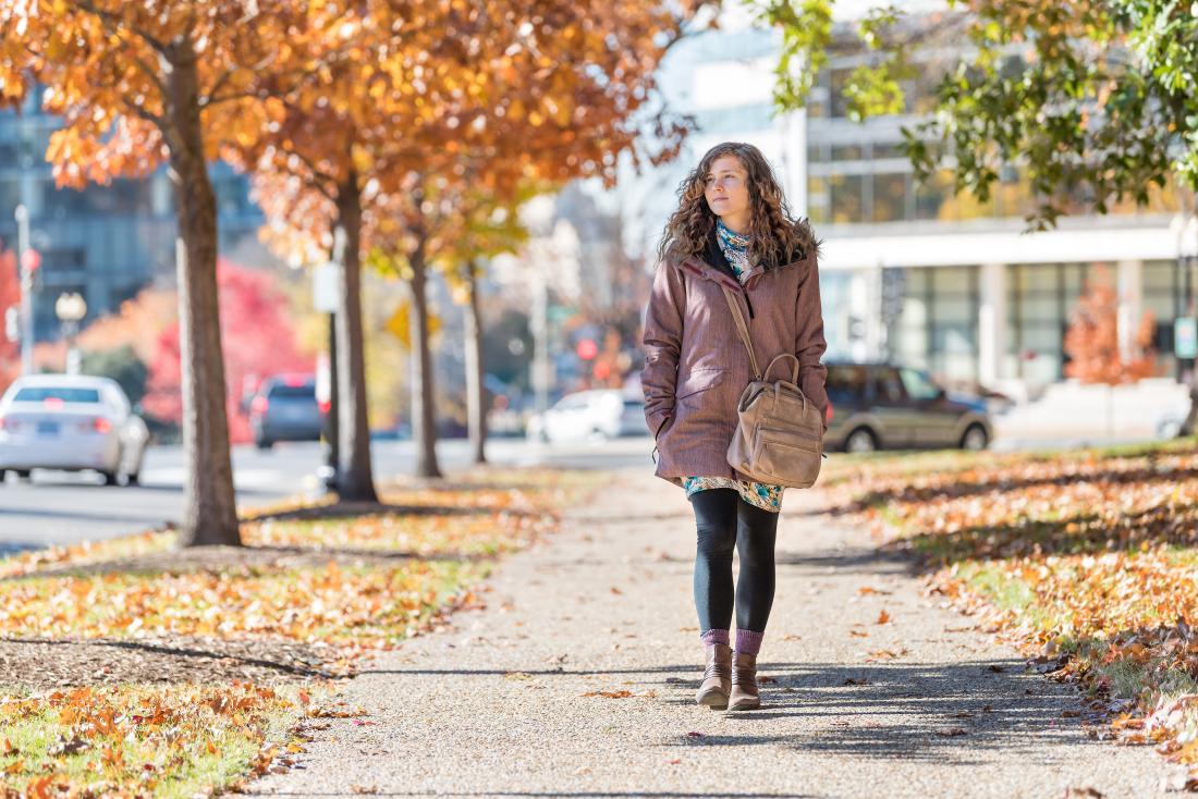 Woman walking through city park in winter coat.