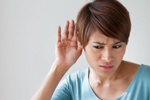 A woman tries to hear out of one ear.