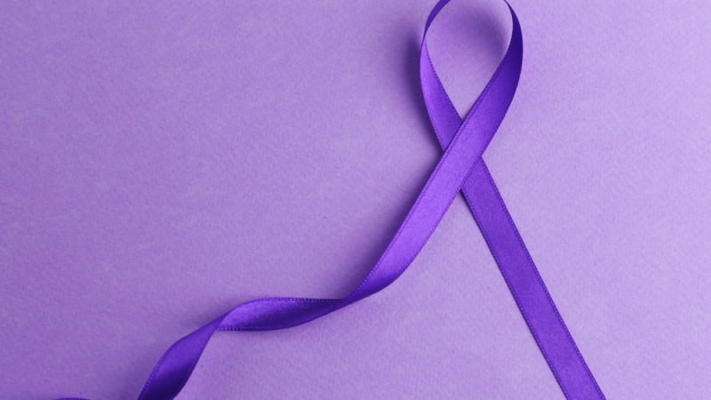 Violet ribbon on color background. Family violence, Alzheimer disease and pancreas cancer concept
