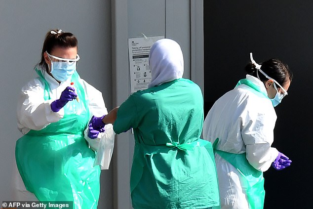 Pictured: Medical staff wear PPE as they prepare to store samples after testing a NHS worker at a drive through at Hopwood Hall College in Rochdale, Greater Manchester