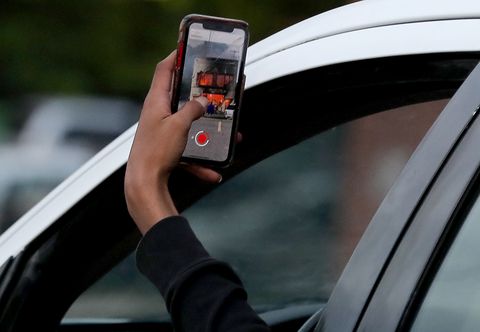 minneapolis, mn may 28 dawn breaks after the second night of unrest in south minneapolis, following the death monday of unarmed george floyd in minneapolis police custody here, a passerby in a car records  a burning building on  e lake street photo by david jolesstar tribune via getty images