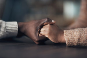 Cropped shot of two people holding hands; concept of support